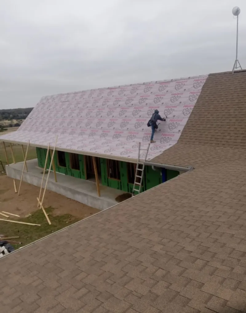 Worker preparing underlayment for a metal roof installation in San Jacinto